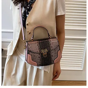 Detail view of stylish snakeskin pattern women crossbody handbag with pink trim and metal lock.