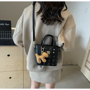 Detailed view of black printed bucket handbag with cute puppy charm, stylish shoulder crossbody bag.