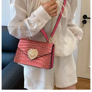 Borsa a tracolla coccodrillo rosa con serratura cuore di perla dettaglio donna.