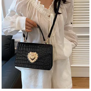 Borsa a tracolla da donna nera con stampa coccodrillo e raffinata chiusura a cuore dorata.