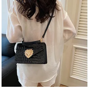 Borsa a tracolla nera con motivo coccodrillo e chiusura a cuore dorata per donna quotidiana.