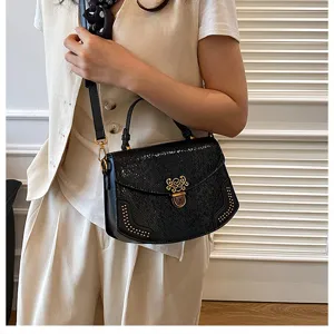 Detail view of the black textured fashion handbag with gold hardware and stylish metal studs.