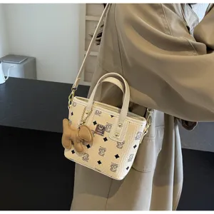 Detailed view of the stylish beige bucket bag with monogram print, chic pendant and handle.