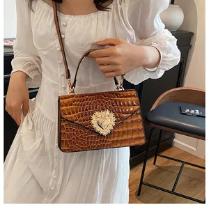 Borsa a tracolla marrone motivo coccodrillo con elegante chiusura a cuore di perle.