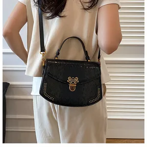 Detail shot of the elegant black snakeskin handbag featuring vintage gold lock and chic rivets.