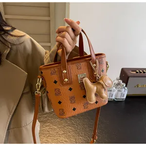 Detailed view of brown printed bucket bag with cute bear charm, elegant crossbody design.