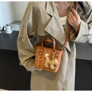 Women canvas bucket bag with cute bear pendant, stylish crossbody shoulder handbag for summer.