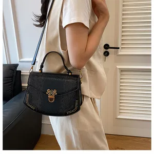 Detailed view of black snakeskin leather shoulder bag with gold hardware and chic clasp.