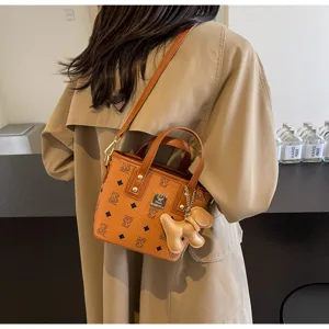 Close-up view of a stylish brown monogram bucket bag with top handle and cute dog charm.