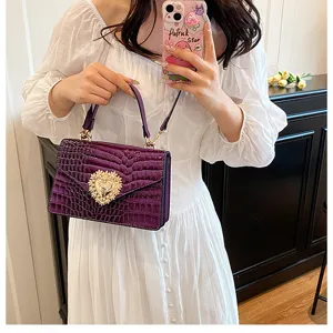 Borsa a tracolla con motivo coccodrillo viola e dettagli con chiusura a cuore dorata.