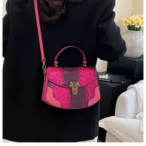 Detailed view of fashionable pink snakeskin crossbody handbag with metal lock and top handle.