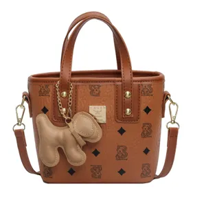 Brown printed bucket bag with top handles, shoulder strap, and cute dog pendant accessory.