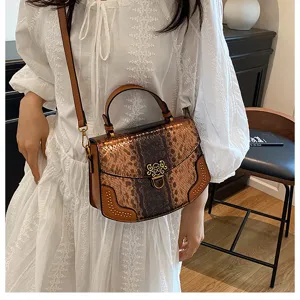 Detail view of brown snakeskin pattern women handbag with metal clasp and shoulder strap.