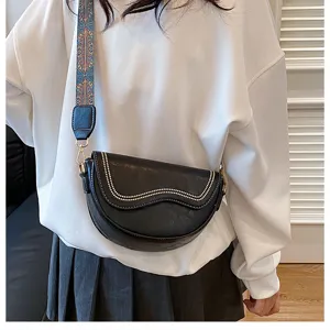 Trendy black saddle bag for women, retro crossbody bag with wide patterned strap and stud trim.