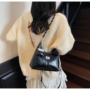 Black patent leather shoulder bag detail, metallic chain strap and turn lock clasp.