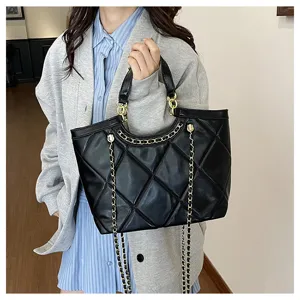 Detailed view of the black quilted tote bag with elegant gold chain strap and handle.