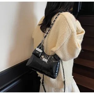 Detailed view of the stylish black patent leather shoulder bag with chic chain strap.