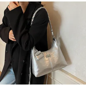 Chic silver metallic hobo shoulder bag with chain strap and stylish metal turn-lock closure.