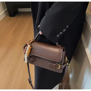 Detailed view of the elegant brown small square bag with chic bead charms and strap.