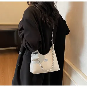 Detailed view of white patent leather shoulder bag with chain strap and cute mini charm.