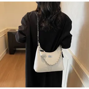 White patent leather shoulder bag detail, featuring metallic chain strap and turn-lock closure.