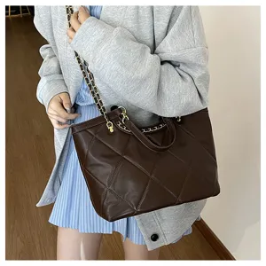 Closeup detail of women's dark brown quilted tote bag featuring metal chain shoulder strap.