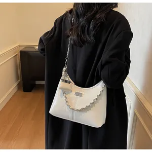 White patent leather shoulder bag detail showing silver chain strap and mini coin pouch accessory.