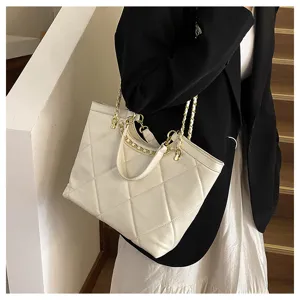 Detailed view of the elegant white quilted tote bag featuring stylish gold chain and handles.