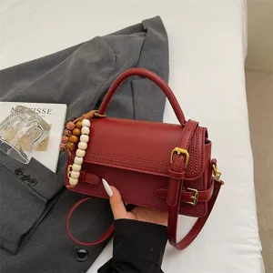 Stylish red leather small square handbag for women, elegant shoulder crossbody bag with bead decor.