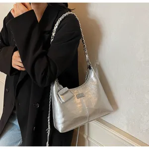 Silver metallic shoulder bag detail, modern chain strap and cute mini pouch accessory.