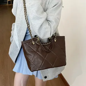 Brown quilted tote bag with chain strap worn by model, large capacity commuter handbag.