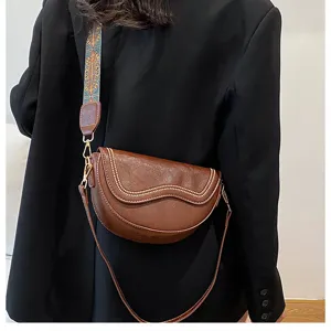 Detail view of retro brown saddle crossbody bag featuring stylish wave flap and wide strap.