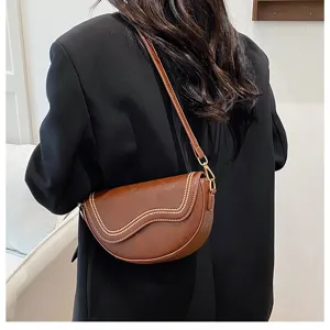 Detail view of the elegant brown leather saddle shoulder bag showing texture and trendy design.