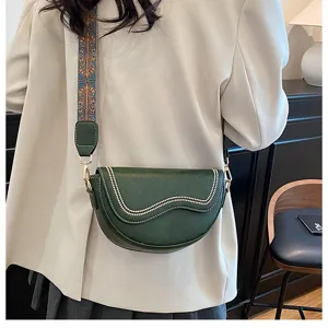 Green saddle bag detail view showing curved flap design and stylish ethnic wide strap.