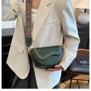 Green saddle bag detail showing wide embroidered strap, elegant wave stitching and hardware.