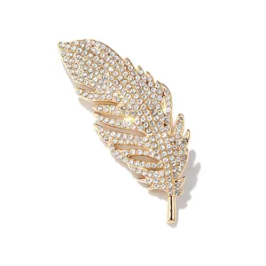 Detailed view of a gold-plated feather brooch encrusted with sparkling clear rhinestones for chic apparel.