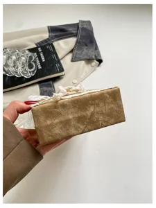 Closeup of the brown crinkled box handbag featuring delicate white lace trim and ribbon detailing.