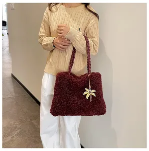Detalle de bolso tote mullido rojo oscuro con asas trenzadas y colgante de palmera.