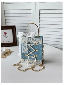 Detail shot of a cute Lolita book-shaped handbag in blue, featuring white lace and bow accents.