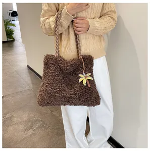 Vista detallada de bolso tote de felpa marrón con asa trenzada y bonito colgante de palmera.