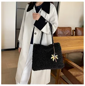 Vista detallada del bolso tote negro esponjoso con asas trenzadas y un bonito colgante chic.