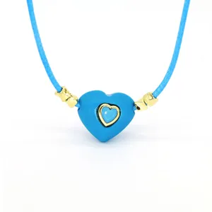 Blue heart wax rope necklace detail showing the vibrant pendant and golden metal accessories.