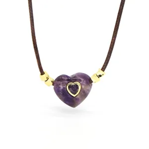 Close-up detail of the purple amethyst heart pendant with gold accent and brown cord necklace.