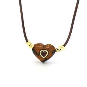 Close-up of natural stone heart pendant necklace with brown braided wax cord and crystal inlay.