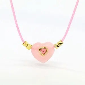 Close-up of pink heart crystal pendant necklace with delicate gold accents and pink cord.