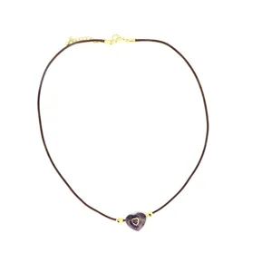Detail shot of the purple crystal heart pendant on a brown wax cord necklace, elegant and chic.