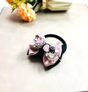 Superbe chouchou avec nœud papillon en strass, ruban rose et noir pour coiffure élégante.
