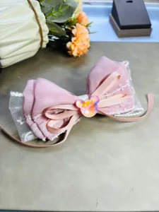 Vue détaillée d'un nœud de cheveux en tissu rose avec dentelle fine et charm scintillant.
