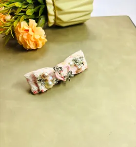 Gros plan détaillé sur la pince à cheveux en dentelle rose, perles et strass brillants.