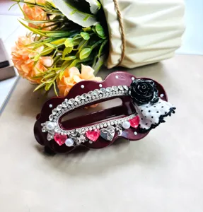 Gros plan détaillé d'une pince à cheveux rouge foncé avec strass, rose noire et nœud.